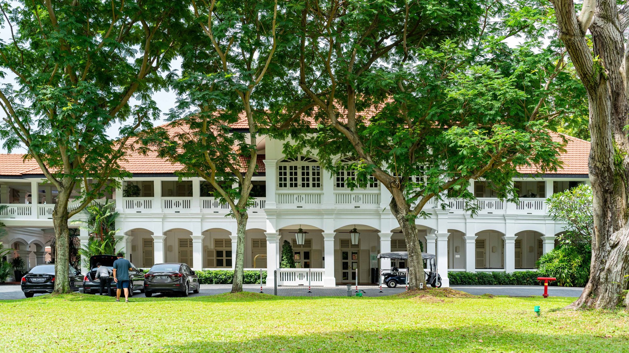 The white colonial bungalow at the front of the hotel, under old rain trees