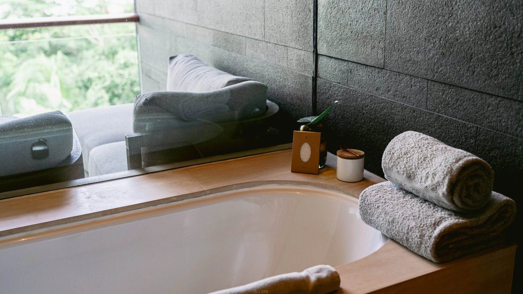 The bathtub beside the window, with rolled towels
