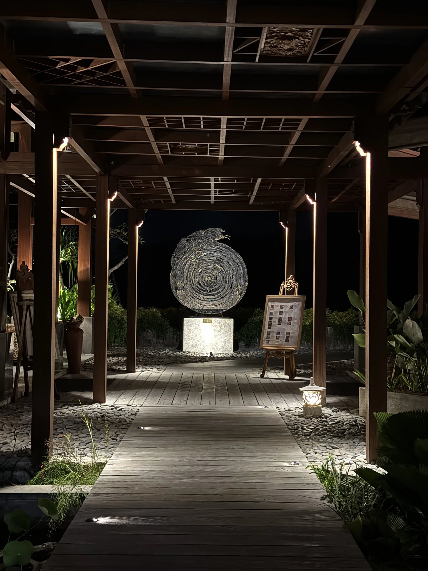 The lit timber walkway to the lobby at night