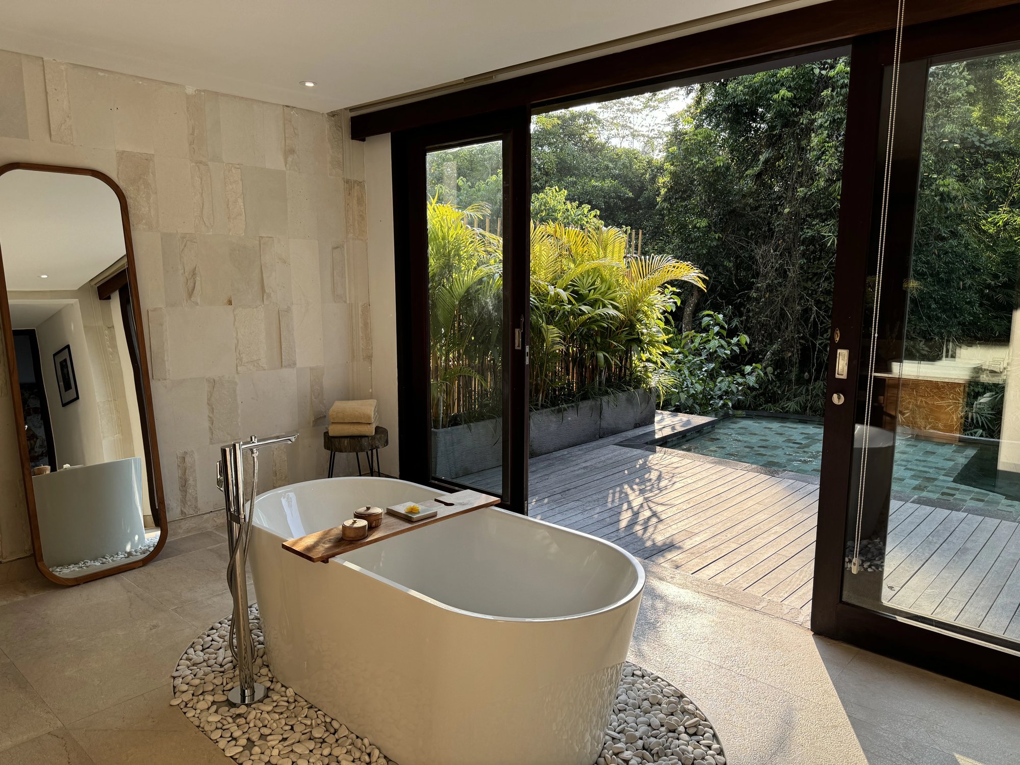 A freestanding bathtub with doors open to the deck and plunge pool