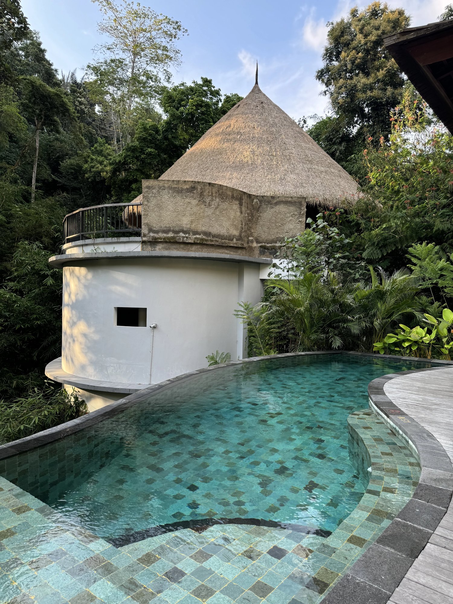 A round tower with a thatched roof beside a pool