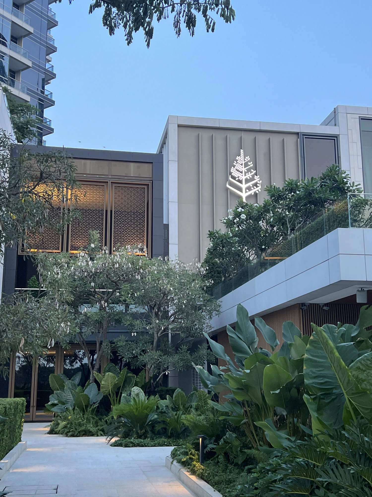 The hotel entrance with the Four Seasons tree logo among tropical planting