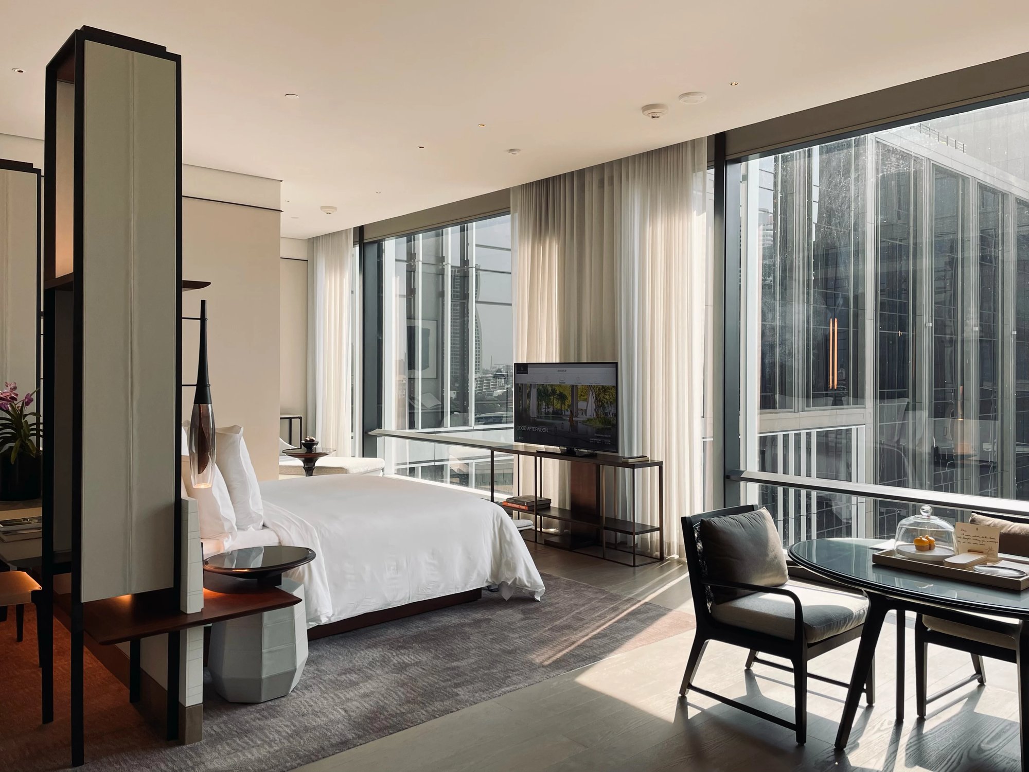 Our suite in afternoon light, with the bed, floor-to-ceiling windows and a table by the glass