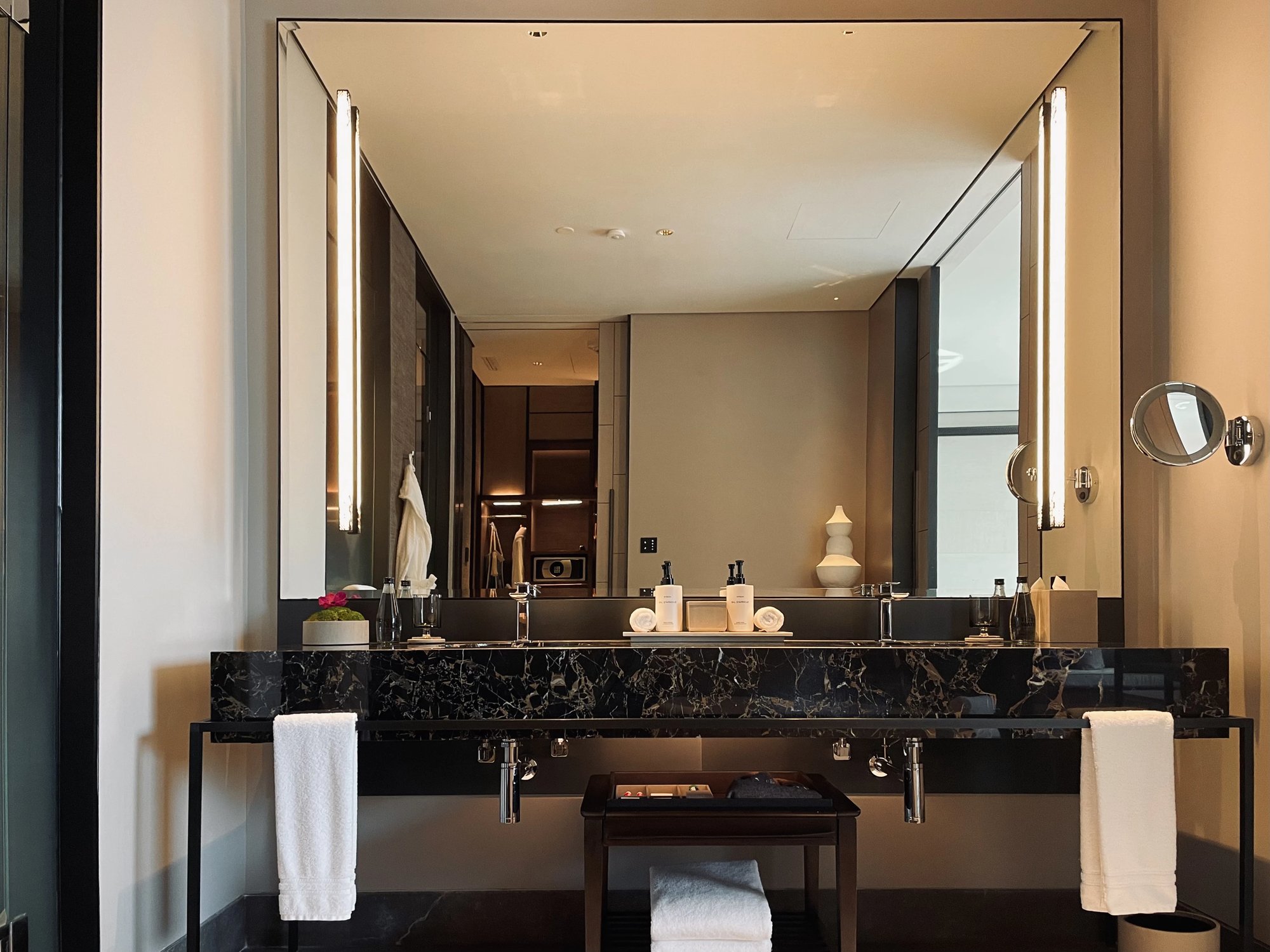The black marble double vanity under a long lit mirror