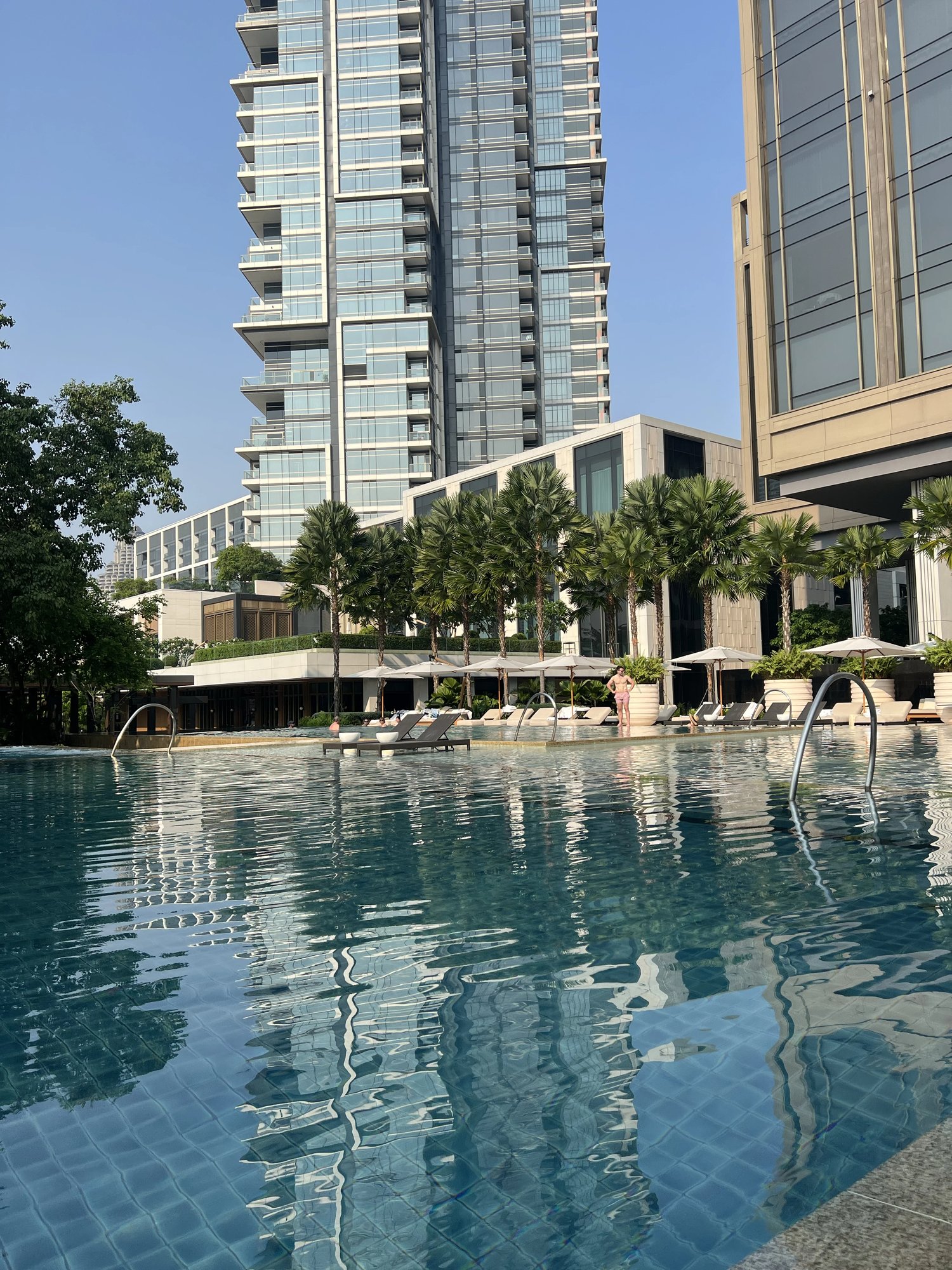 The riverside pool with the hotel tower and loungers behind