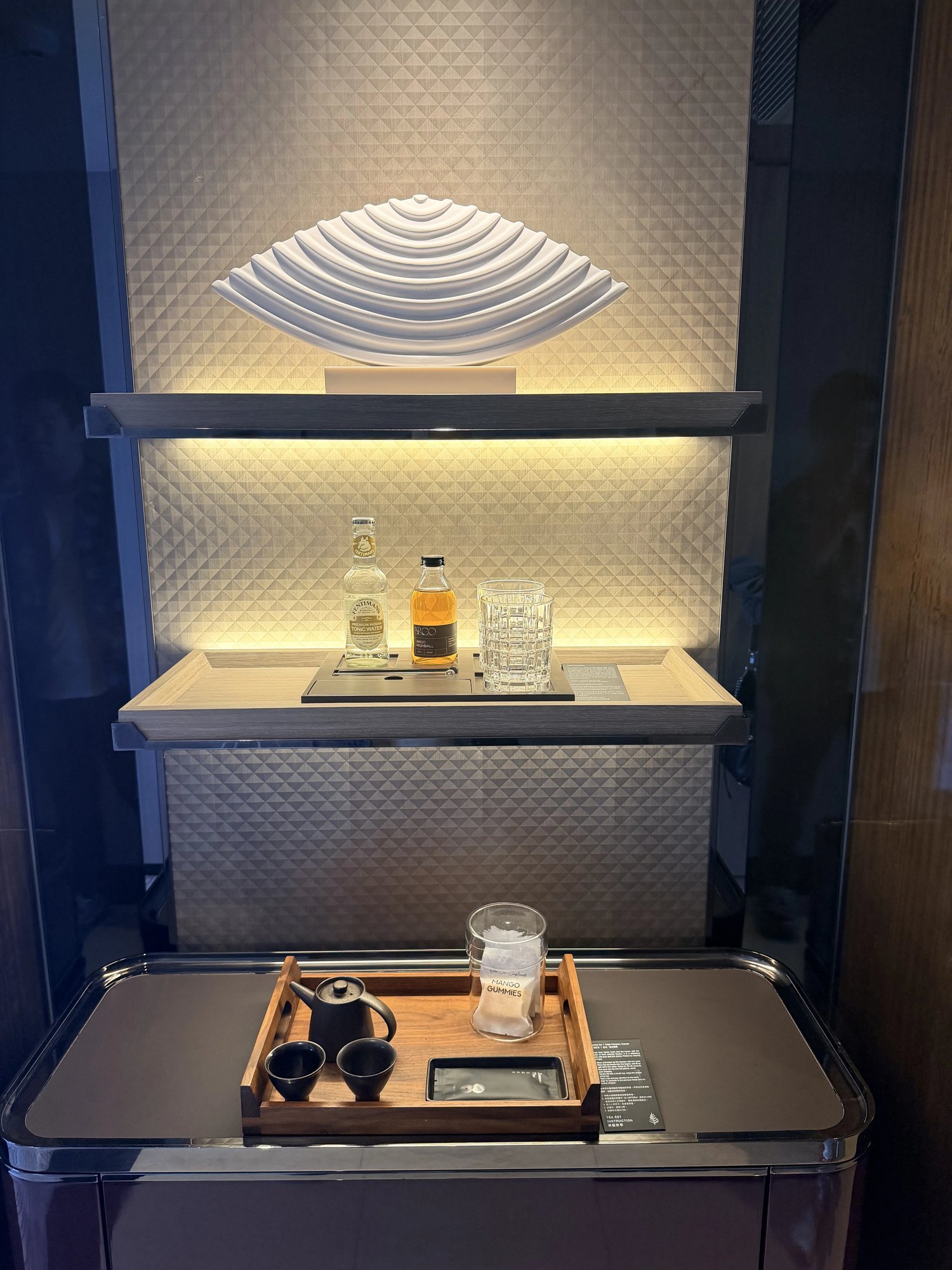 A lit shelf with a shell sculpture and a tea tray