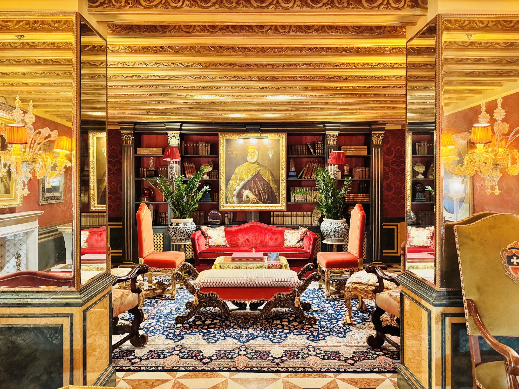 The library lounge with a gilded beamed ceiling and red sofas