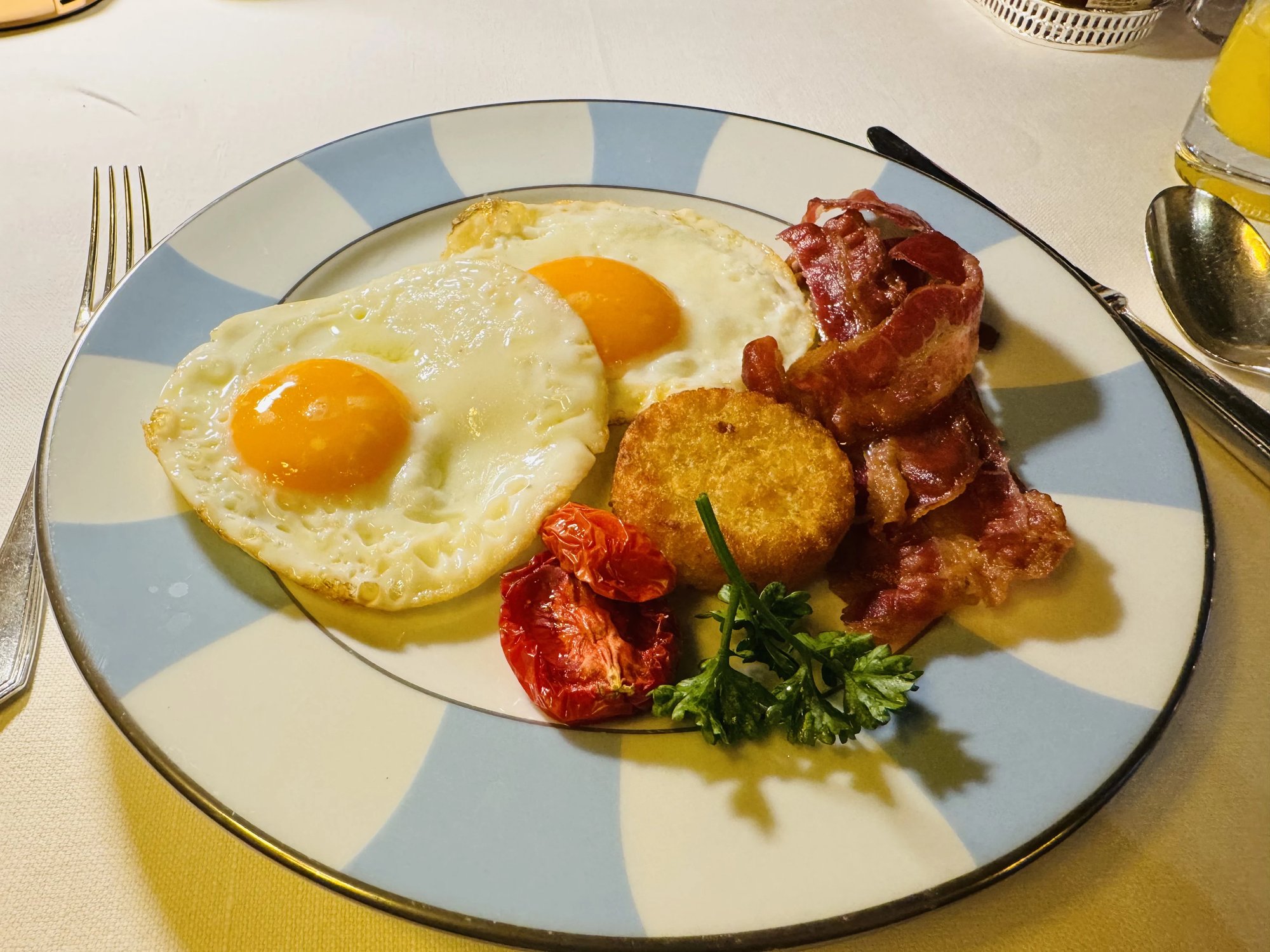 Eggs, bacon and potato on a blue-striped plate