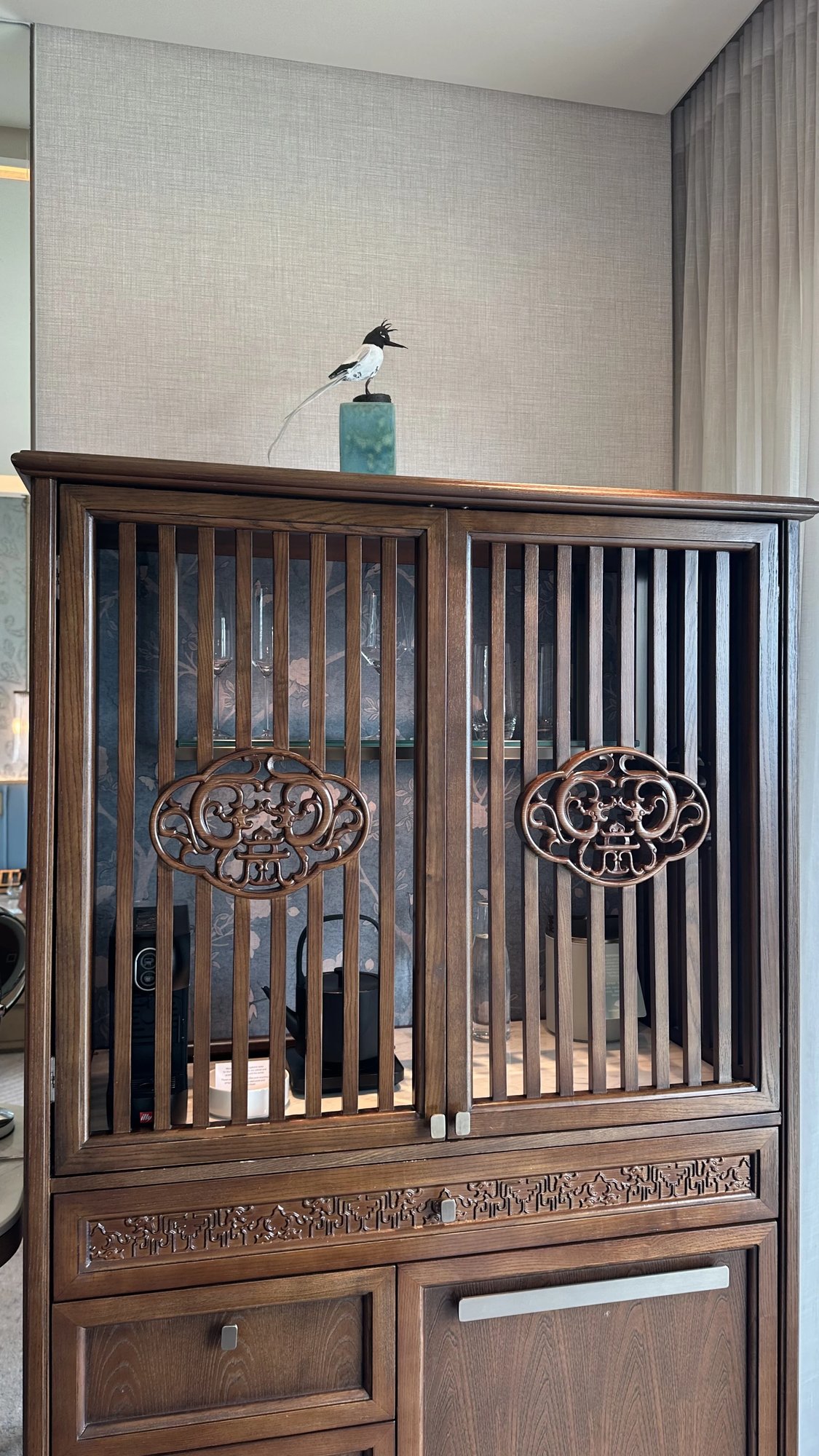 A carved lattice cabinet with a small bird on top