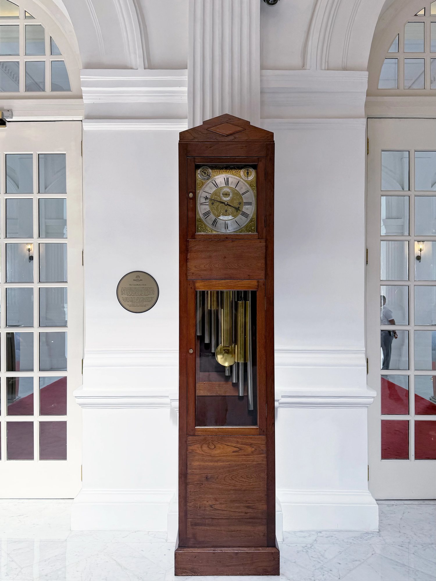 An antique grandfather clock between white doors