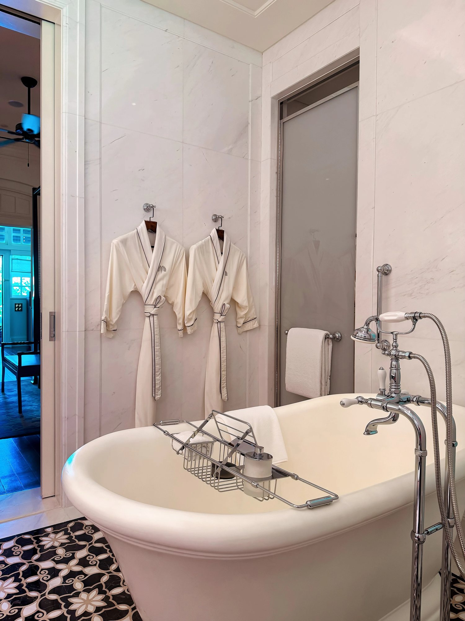 A clawfoot bathtub with two robes hanging above