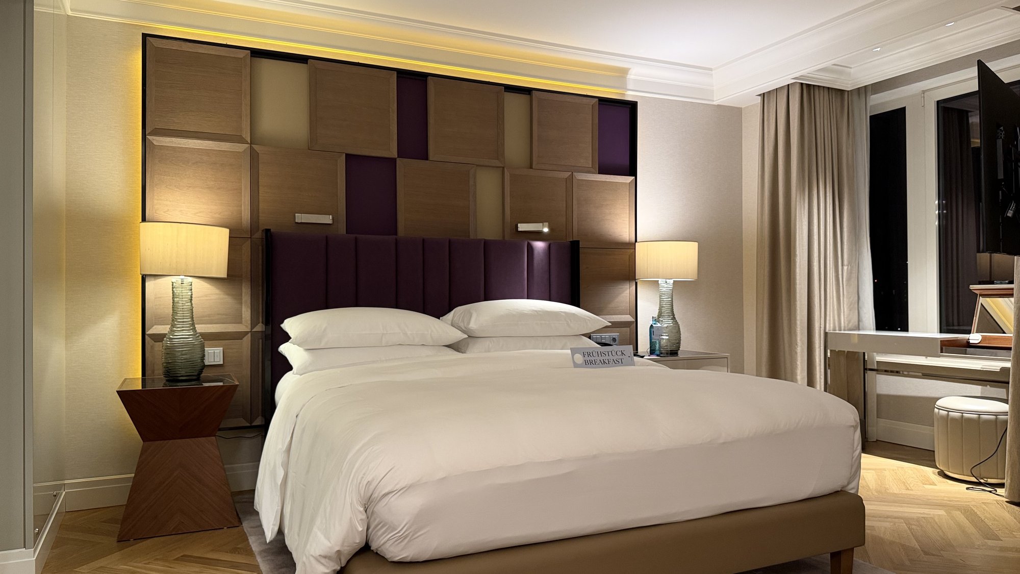 The suite bedroom with a king bed, purple headboard and evening window