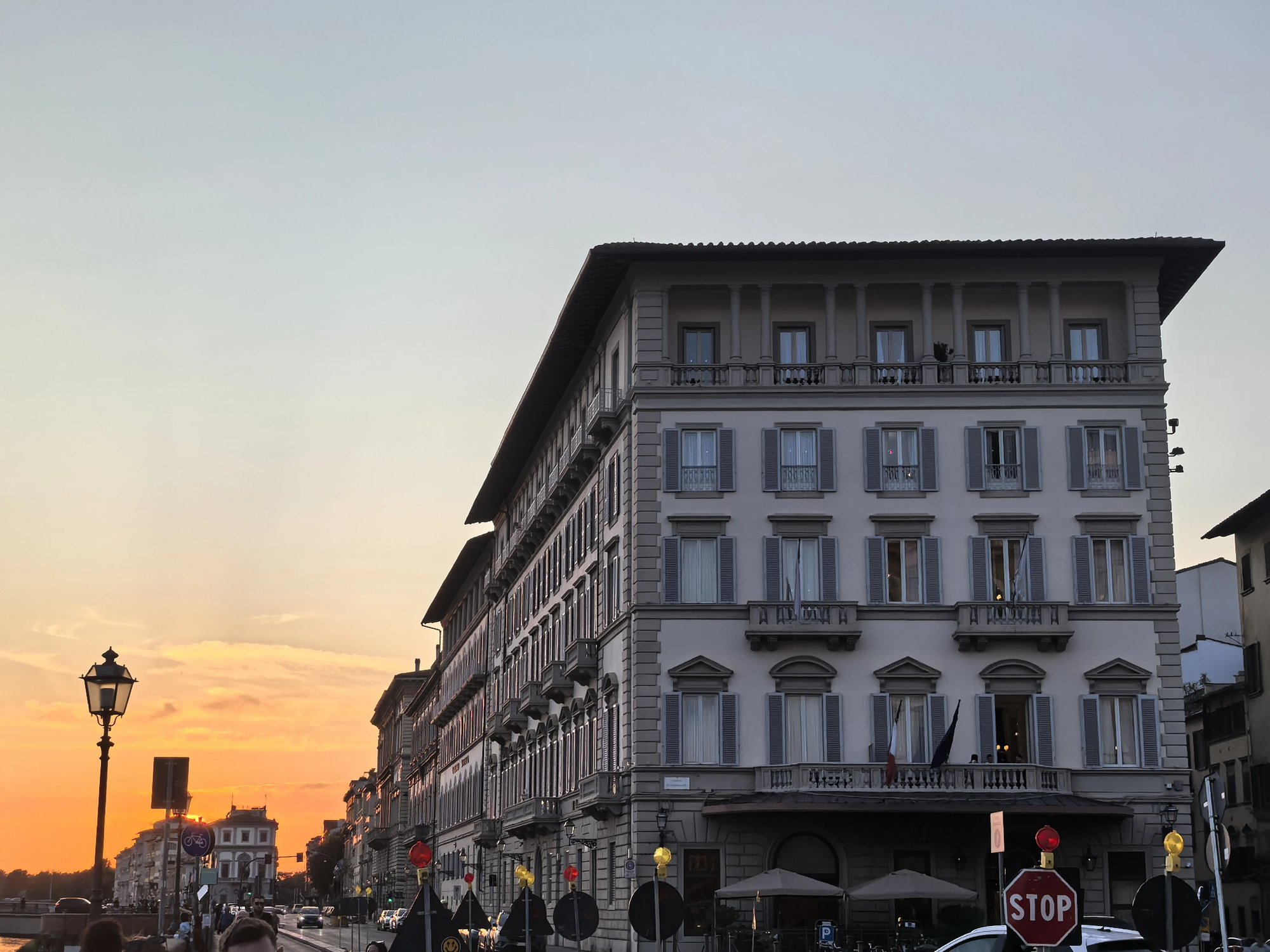 The St. Regis facade at dusk with an orange sky over the Arno embankment
