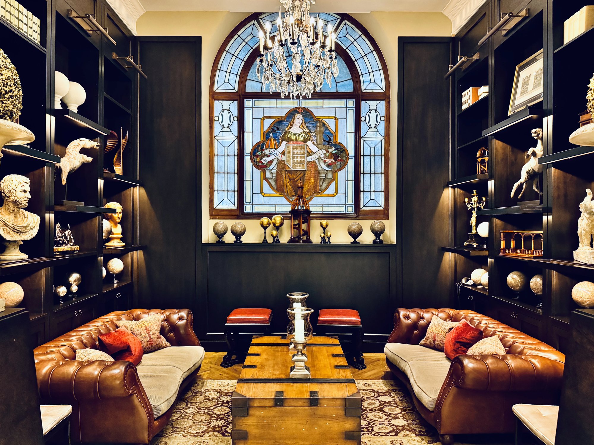 Library lounge with a stained-glass window, leather sofas and busts