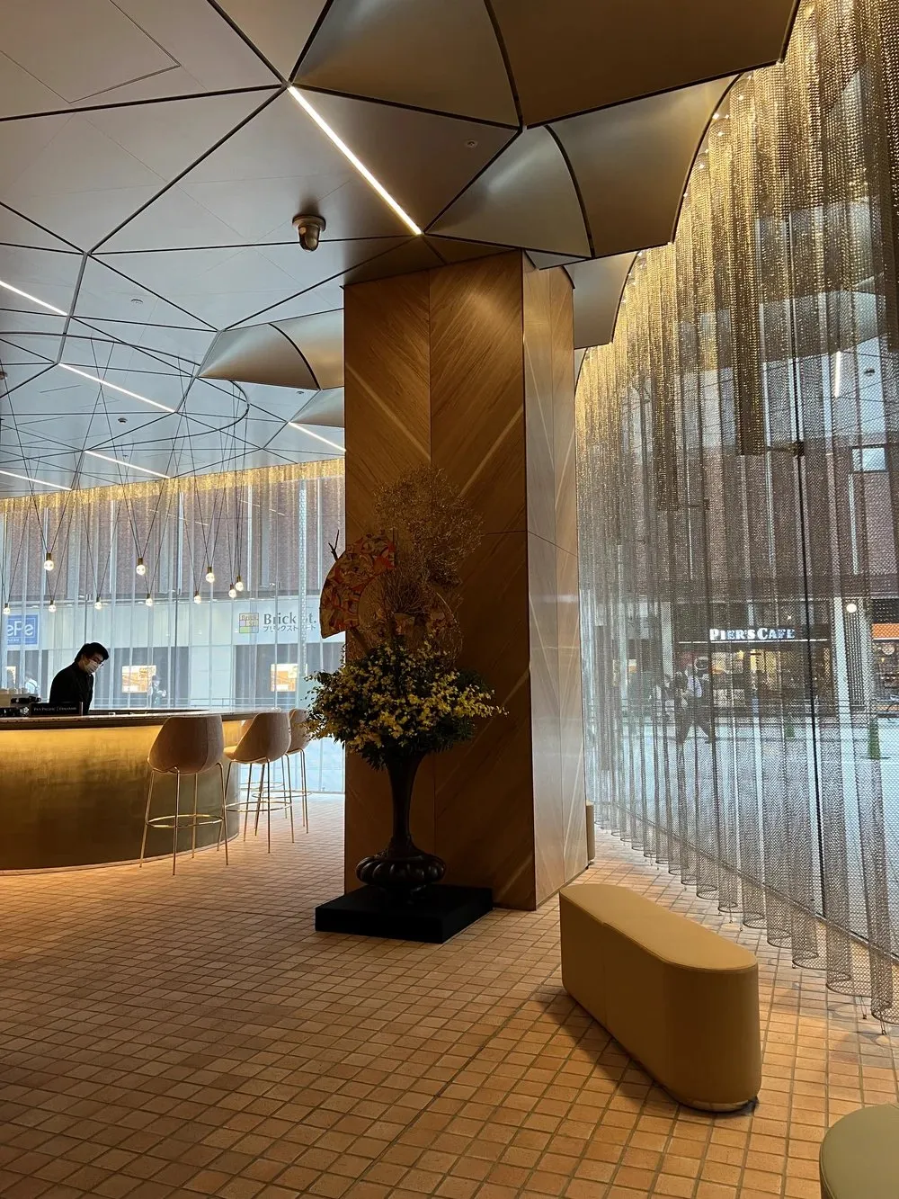 The sky lobby with a gold wood column, flowers and a curtain of metal beads