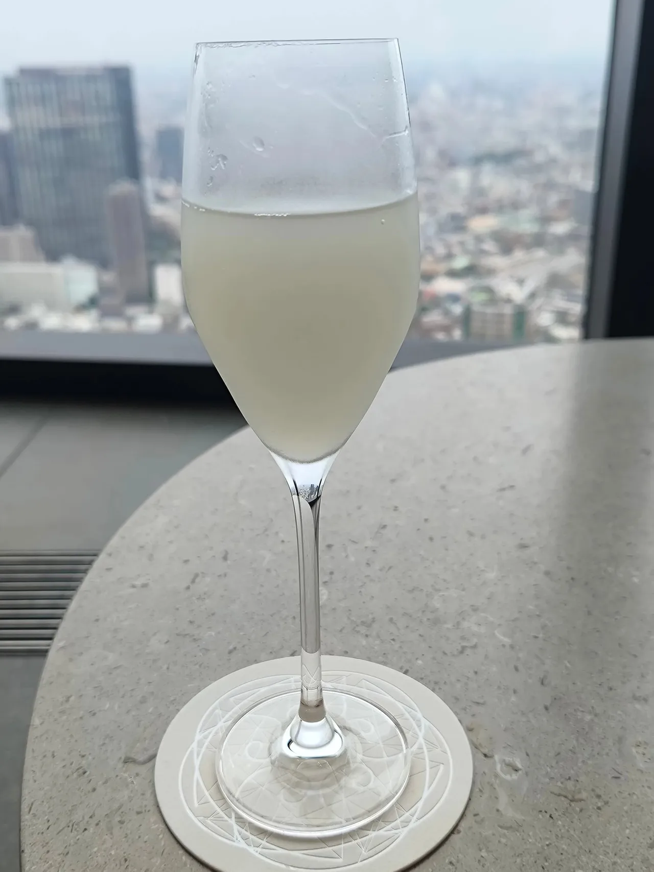 A glass of sparkling drink on a stone table against the city