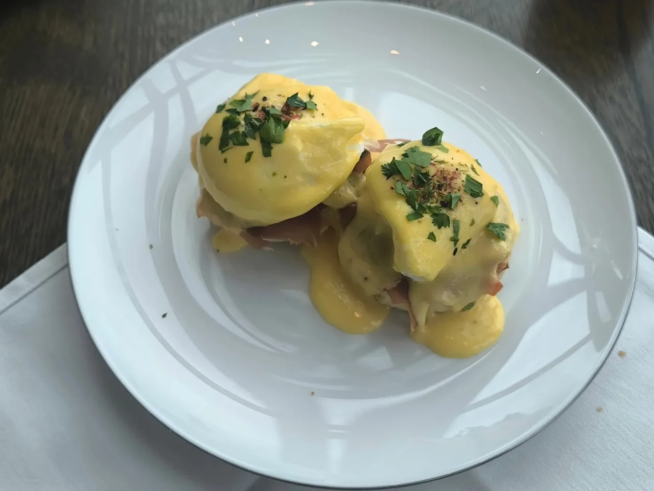 Eggs Benedict with chives on a white plate