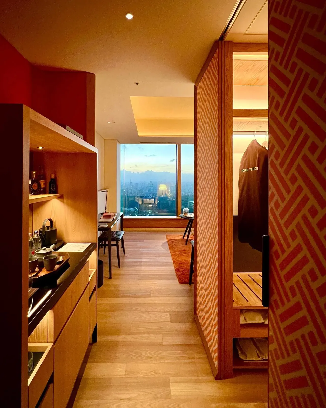 The room entrance hall in pale oak with a screen of red geometric panels, looking through to the window