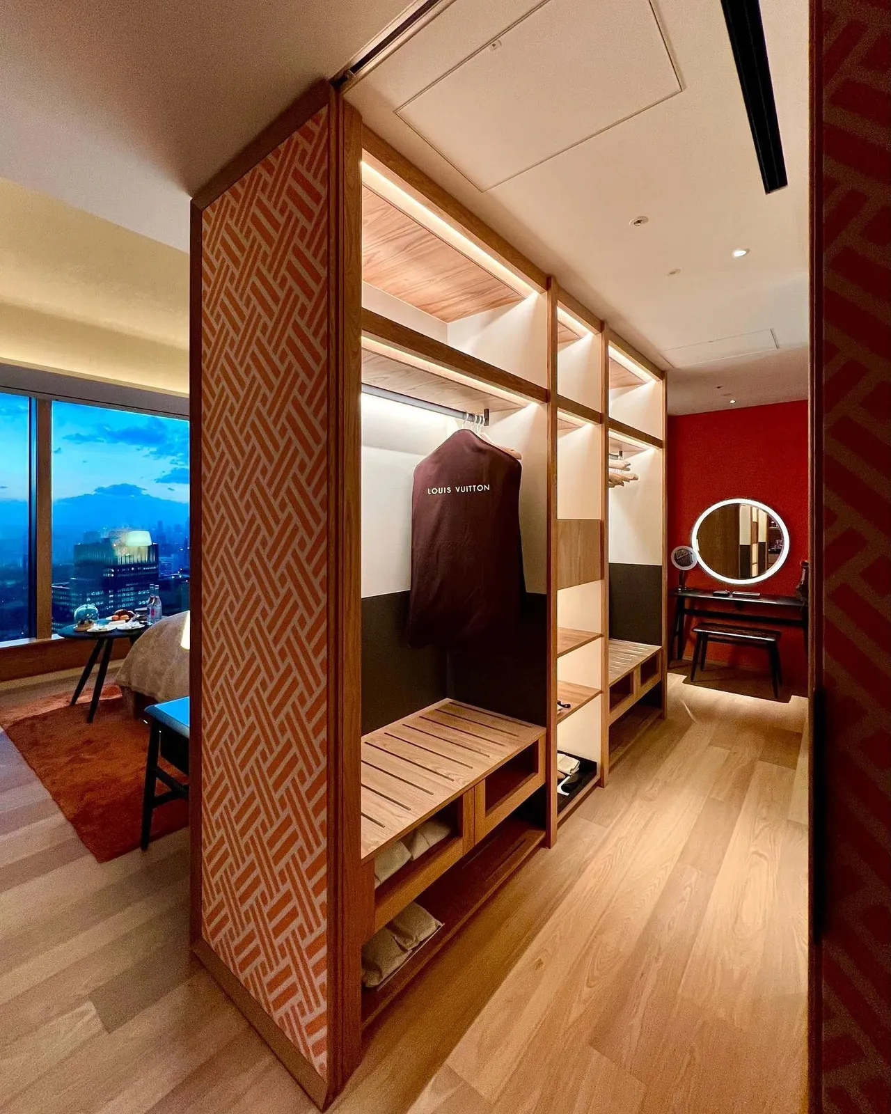 The dressing room beside the window with a wardrobe behind a red patterned screen and the city outside