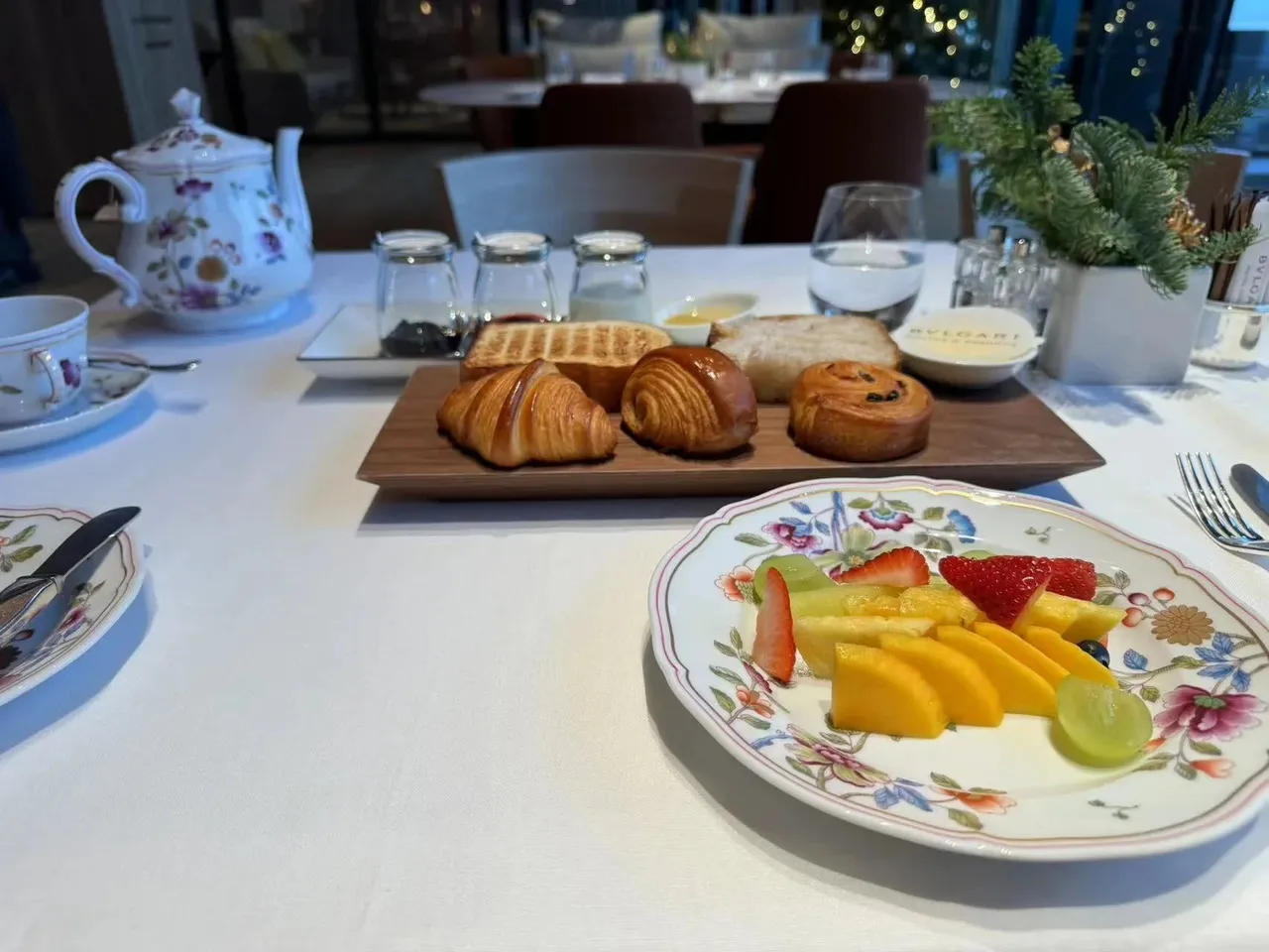 Breakfast pastries and a plate of fresh fruit on white linen