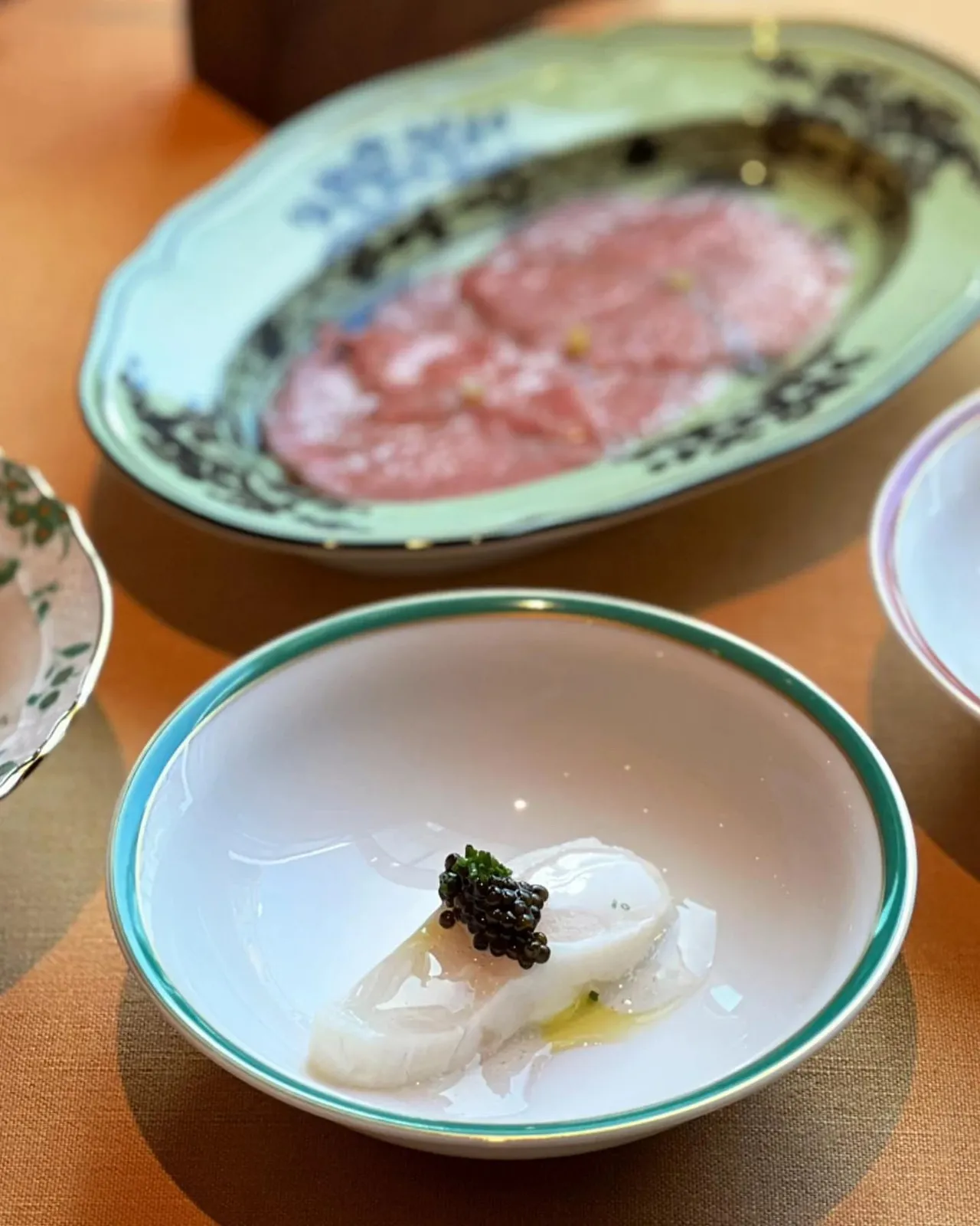 Raw fish with caviar on painted plates
