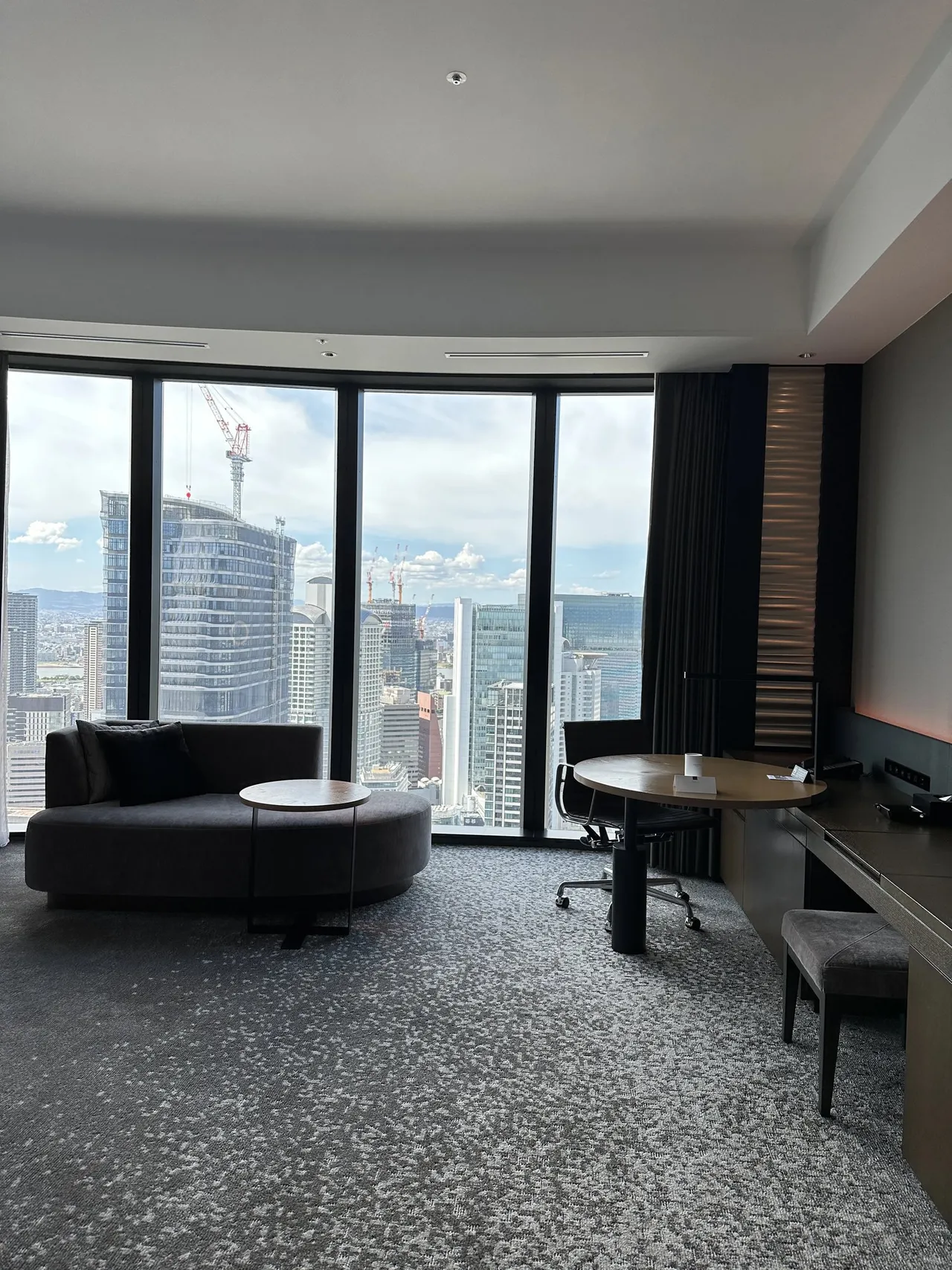 The corner room with floor-to-ceiling windows over the city, a round sofa and a desk