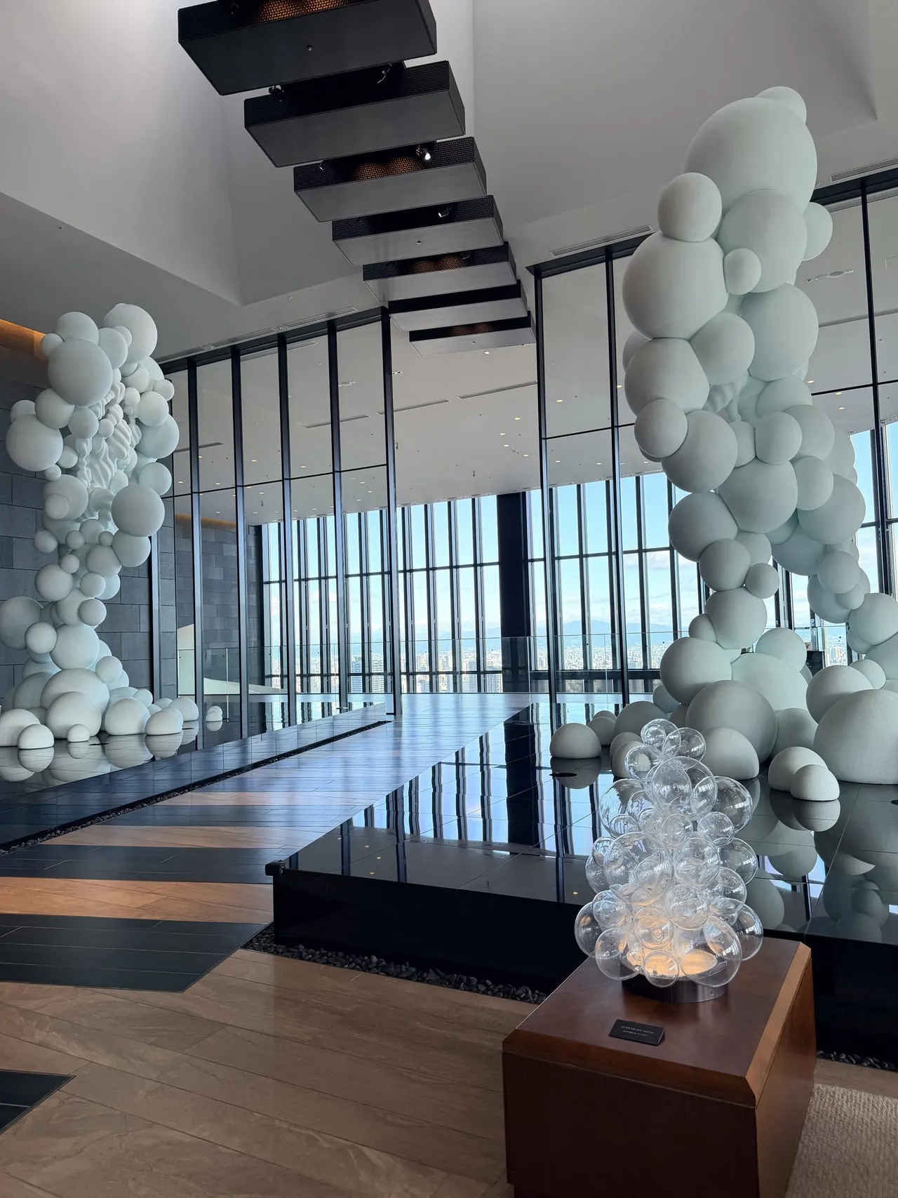 White bubble sculptures and a floating staircase against the 40th-floor lobby windows