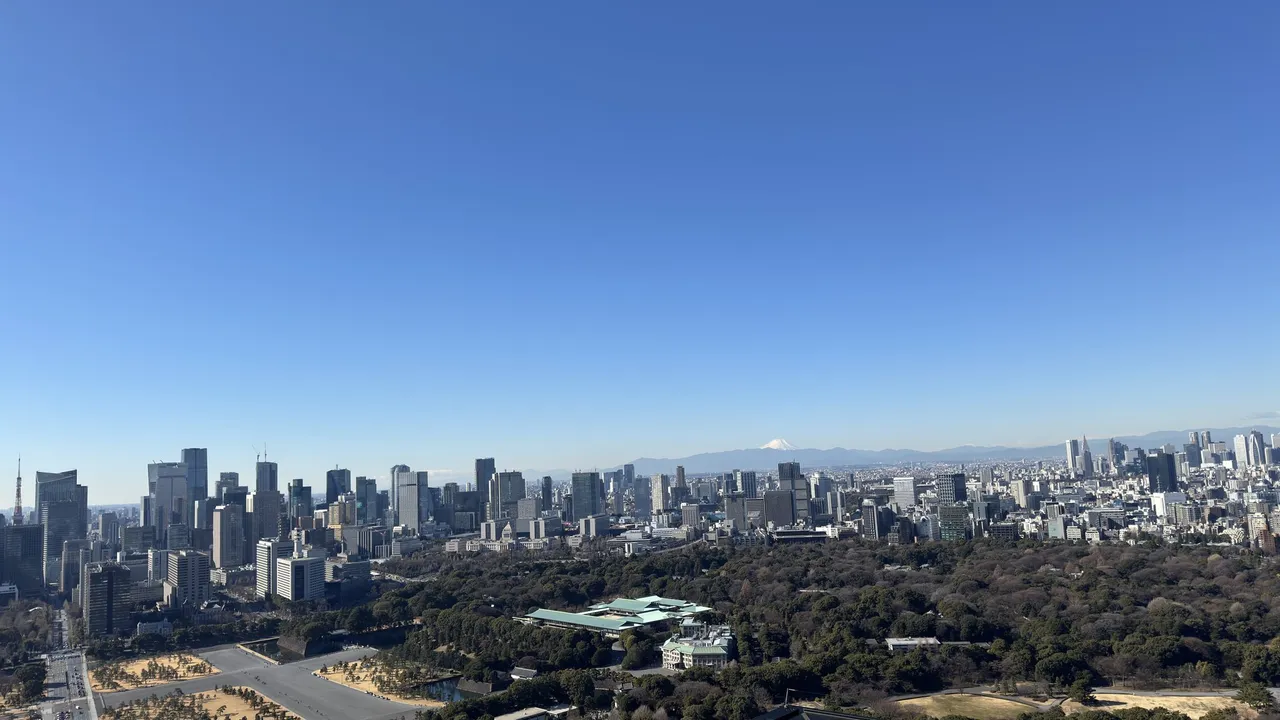 Clear-day panorama over the Imperial Palace gardens and Tokyo towers, with Mount Fuji faint on the horizon