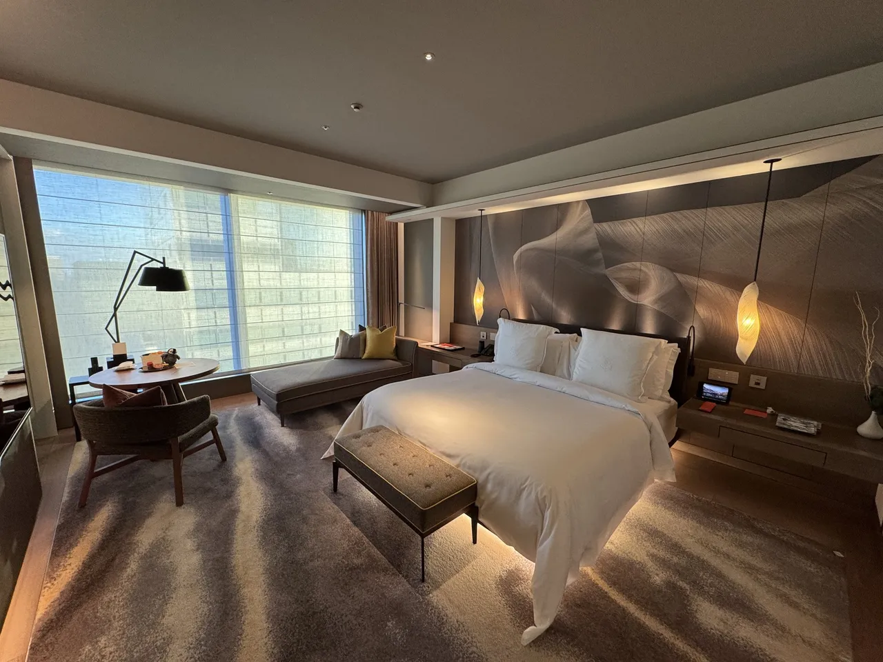 The Superior room with its sculpted headboard wall, bench at the bed foot and skyline windows
