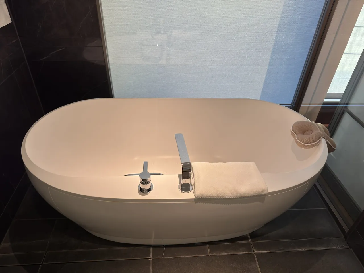 A freestanding tub in front of a frosted window