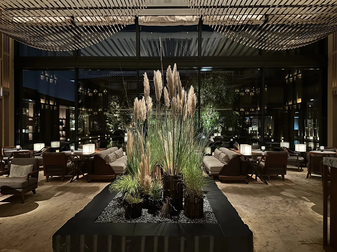 The lobby lounge with a grass-and-plume planting and the courtyard beyond the glass