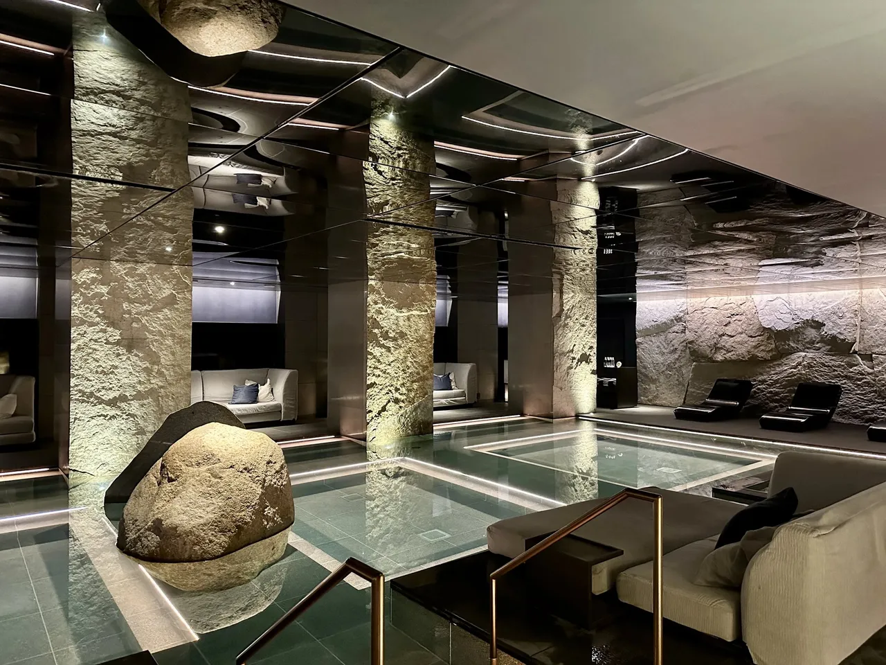 The thermal spring pool with a large boulder and lounge seats