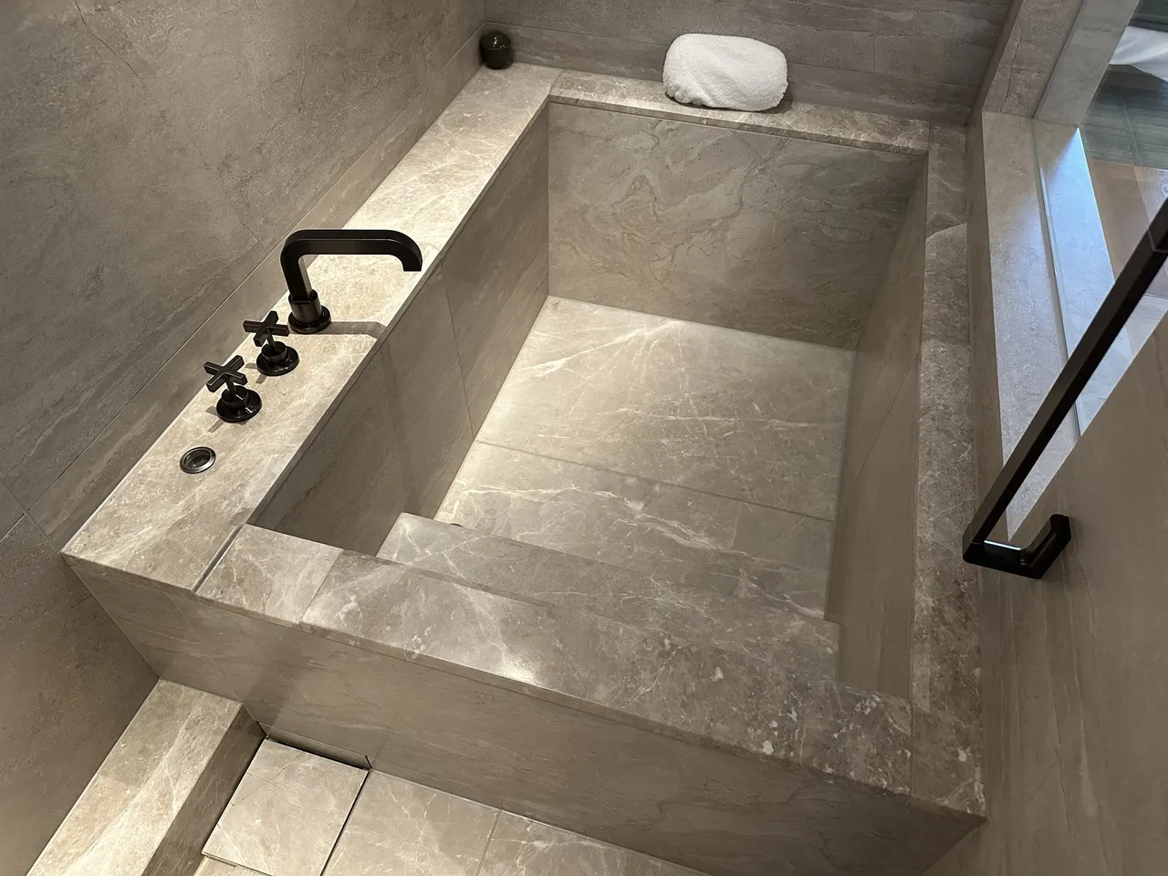 The deep stone soaking tub with a stone-block rim