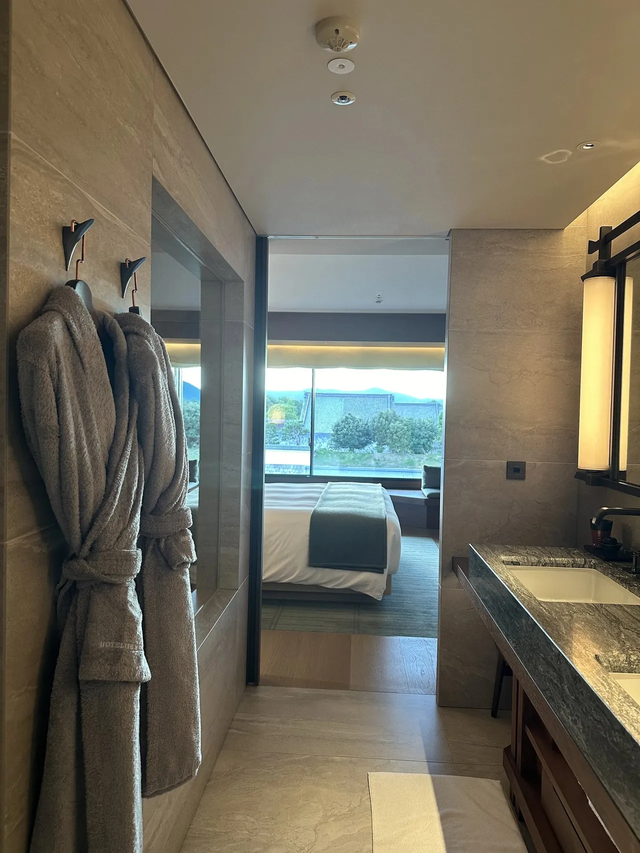 Robes hanging in the bathroom, looking through to the bed and window