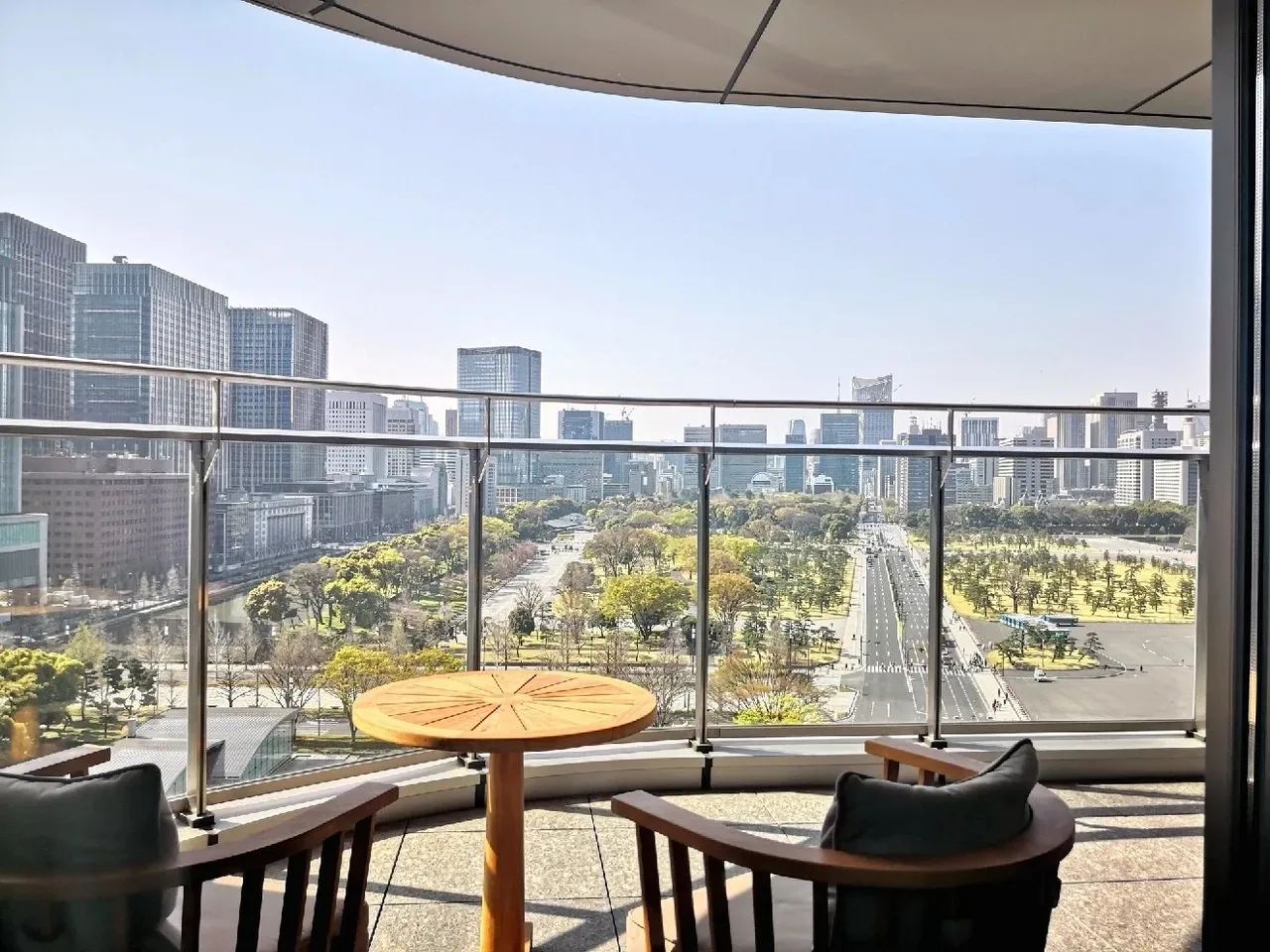 The curved balcony of the ninth-floor room with a teak table and chairs facing the palace grounds