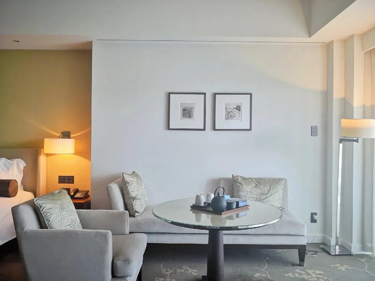 A pale sofa, round tea table and framed prints in the sitting corner of the room