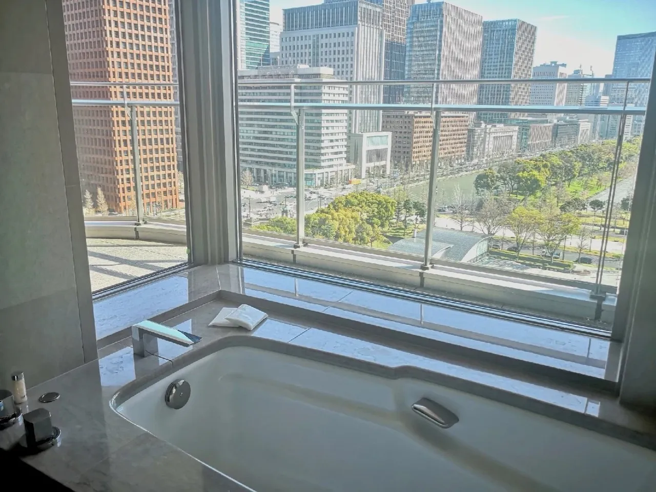 A deep soaking tub set in the bathroom window above the Marunouchi towers and palace park