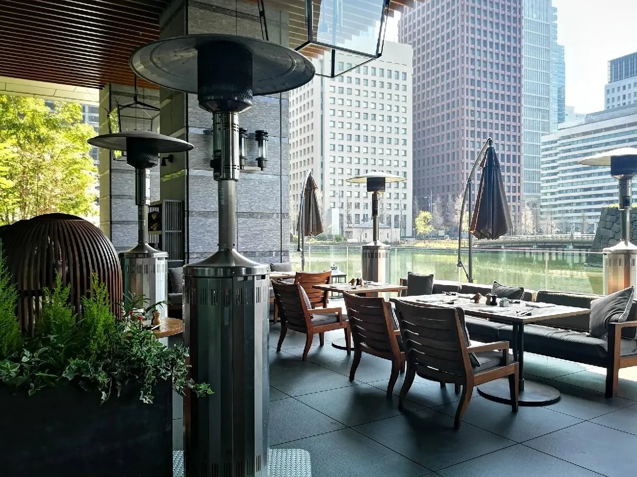 The Grand Kitchen terrace with rattan chairs and patio heaters beside the moat