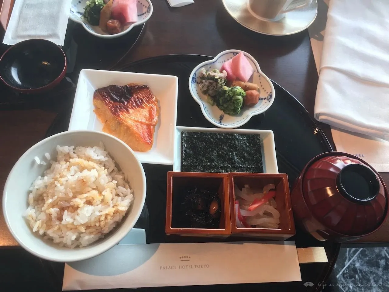 A Japanese breakfast tray with grilled salmon, rice, miso soup and small pickled dishes