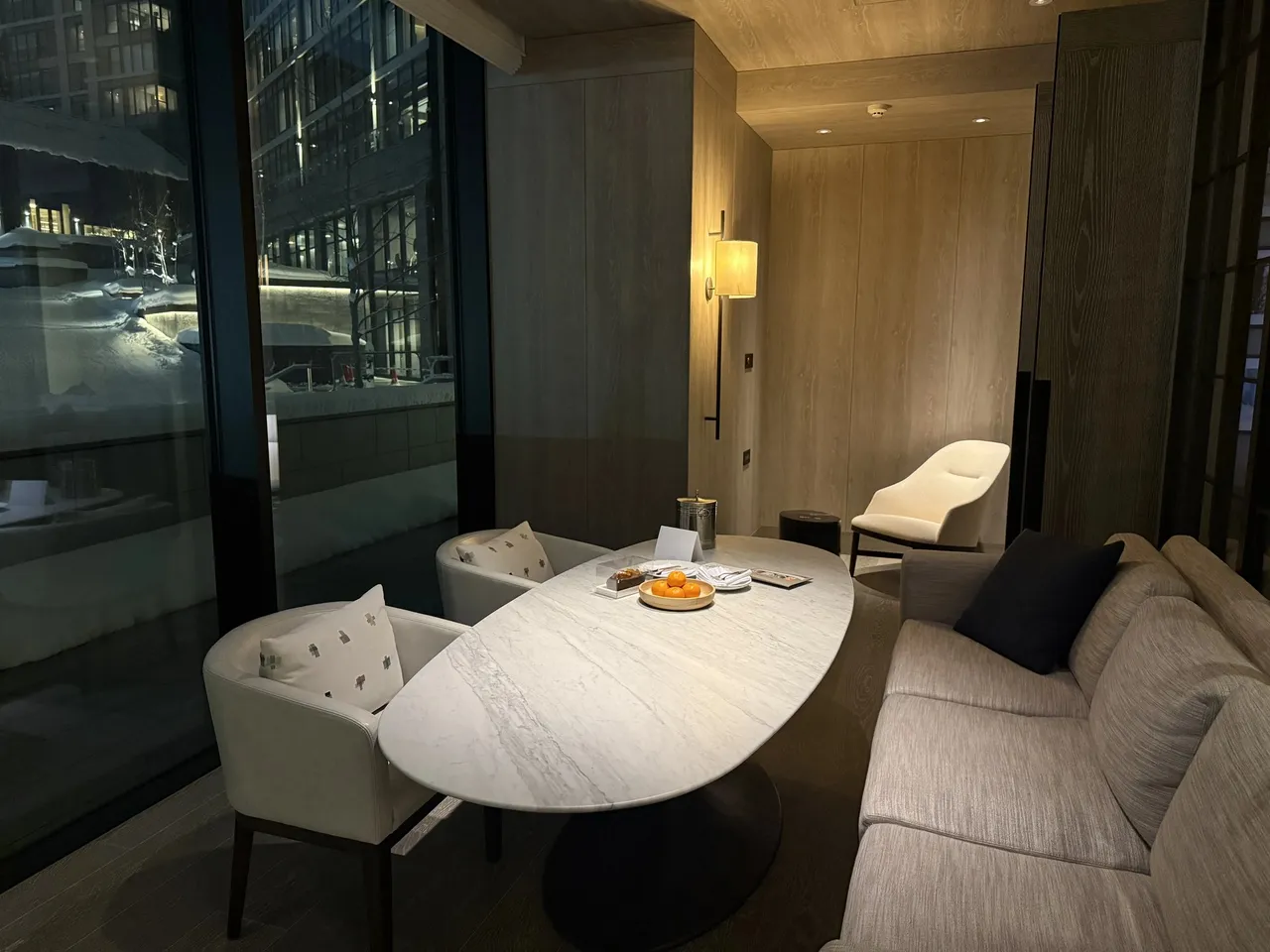 The suite dining table and sofa beside a tall window at night