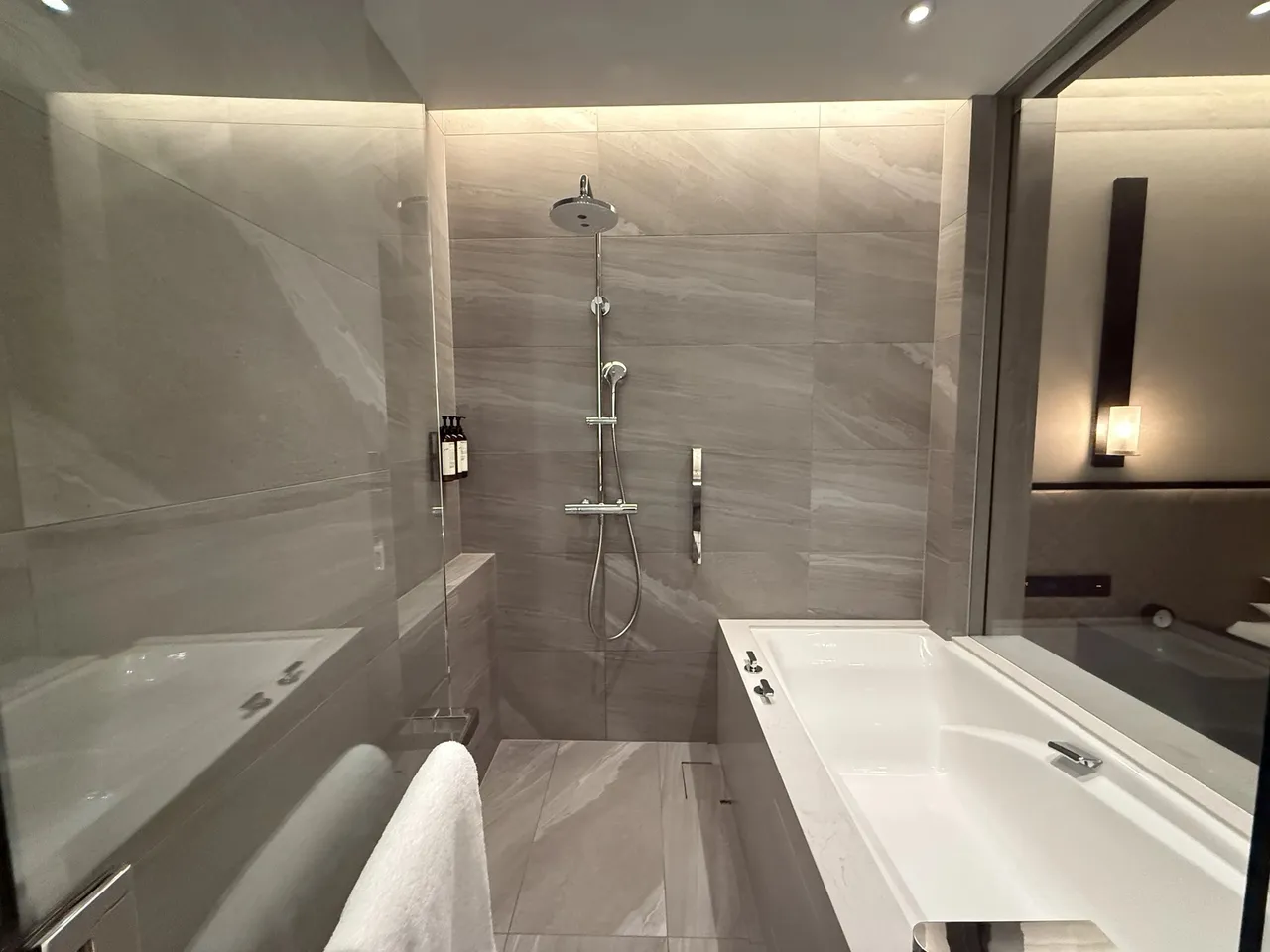 The suite bathroom with a deep tub and rain shower in pale stone