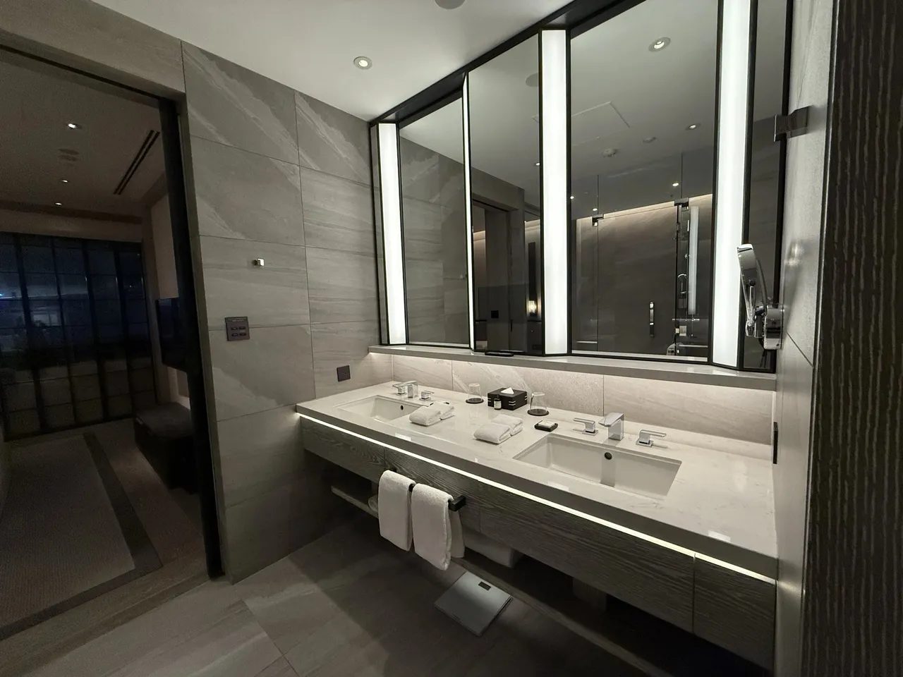 The double vanity under tall lit mirrors