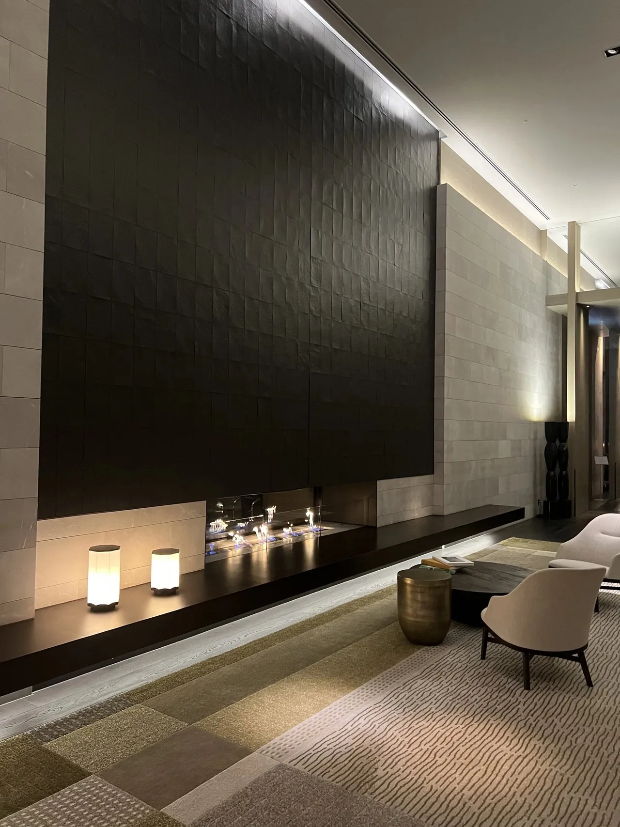 A lounge nook with a dark feature wall and glowing lamps