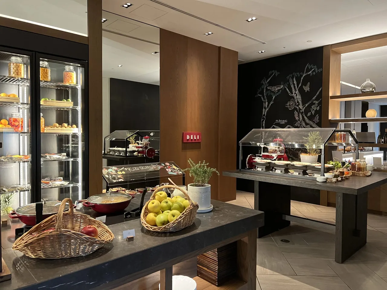 The breakfast room counters with a fruit basket, a deli slicer and a chalk forest mural