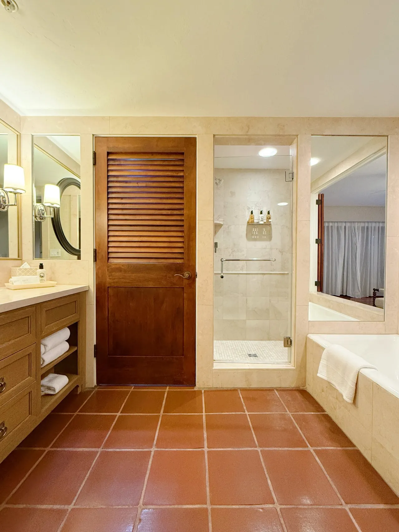 The bathroom with a tub, glass shower and wood vanity