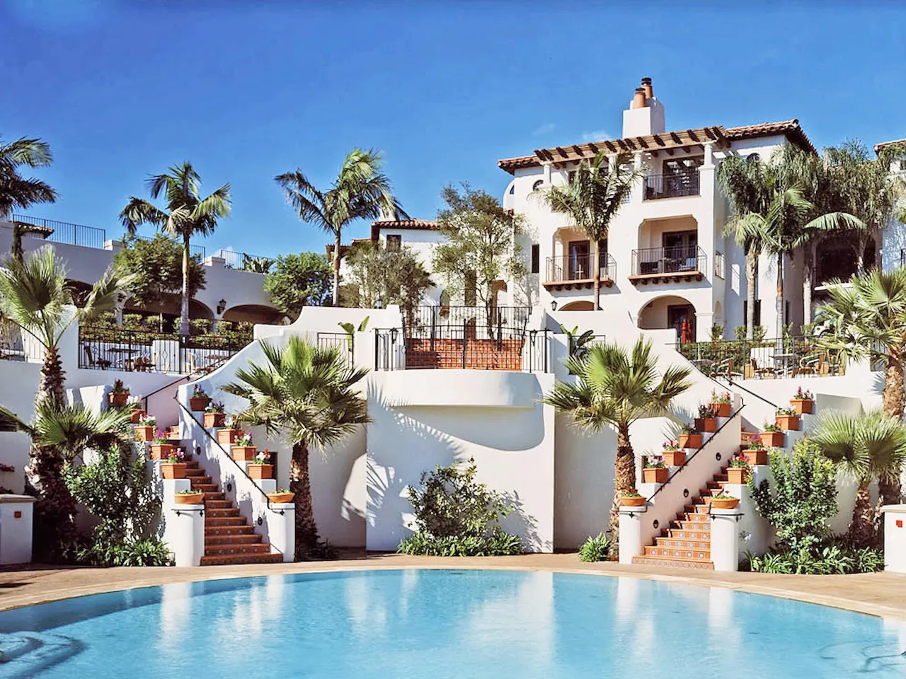 The pool with white Spanish-style buildings and a staircase