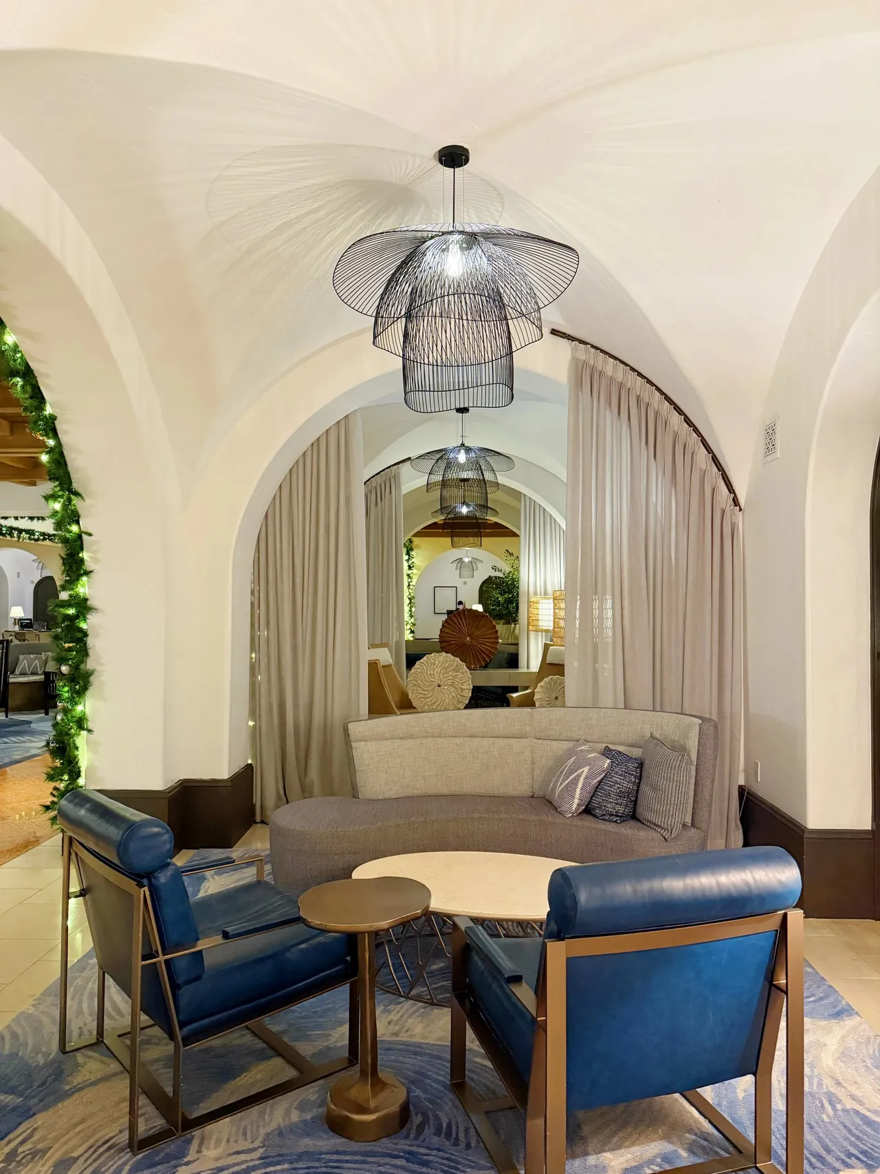 A lounge nook with a pendant lamp and blue armchairs