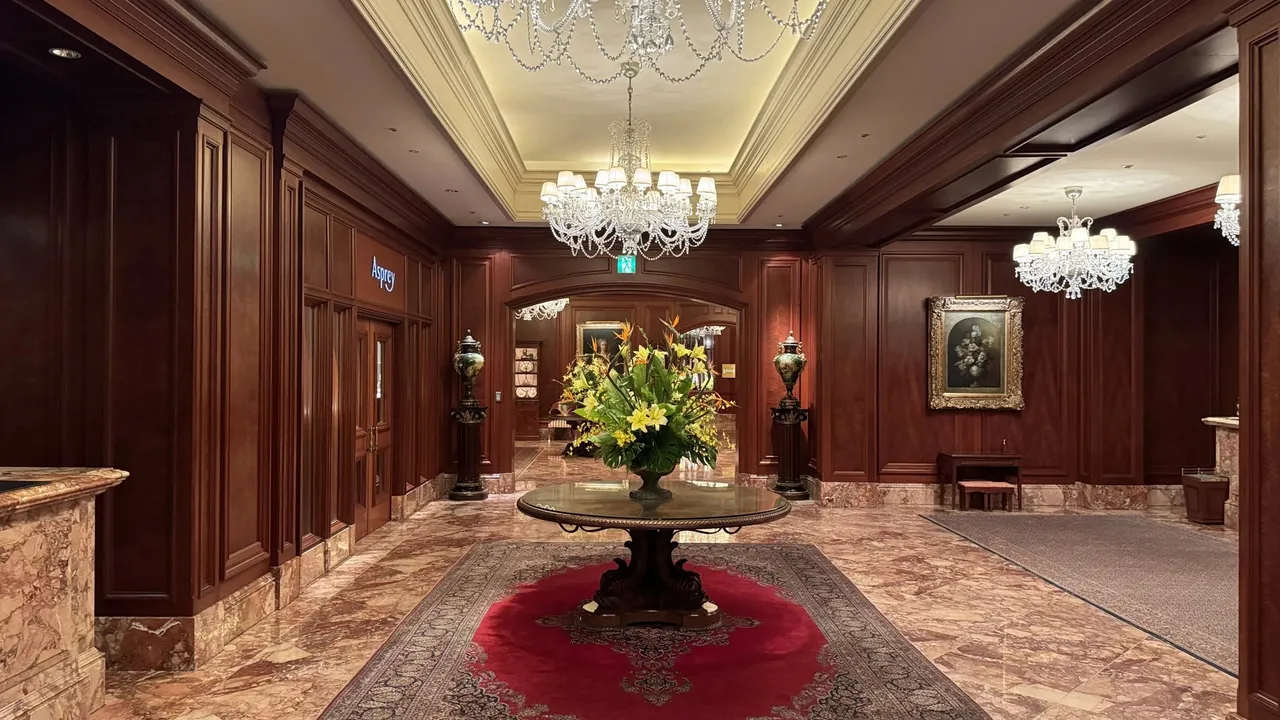 Mahogany-panelled lobby hall with a round flower table and chandeliers