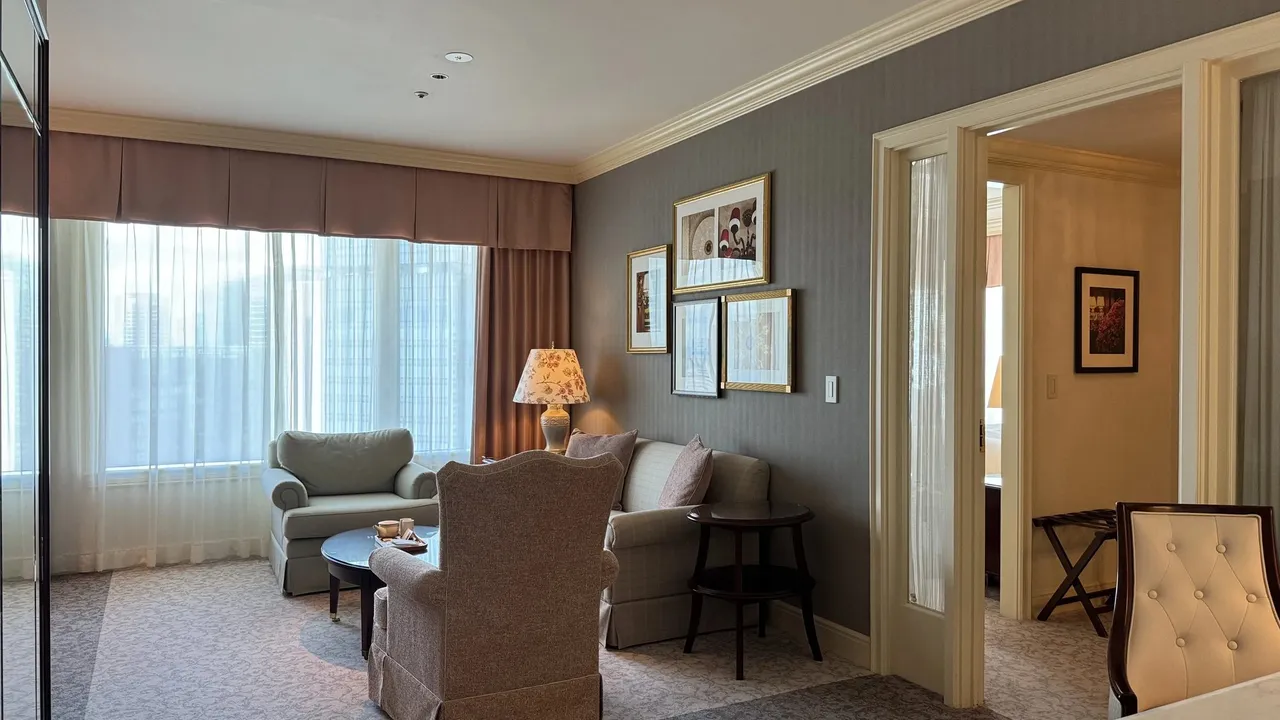 Suite living room with armchairs, a sofa and tall windows