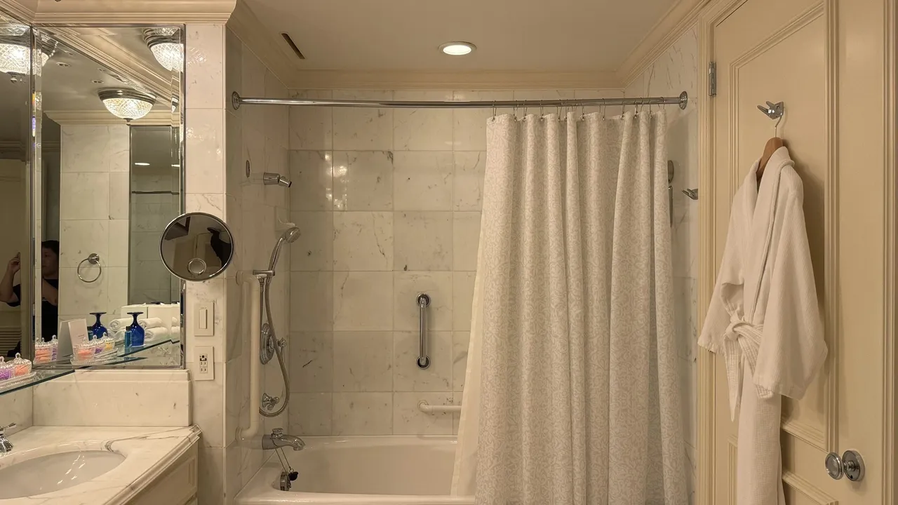 Bath and shower with a white robe on the door